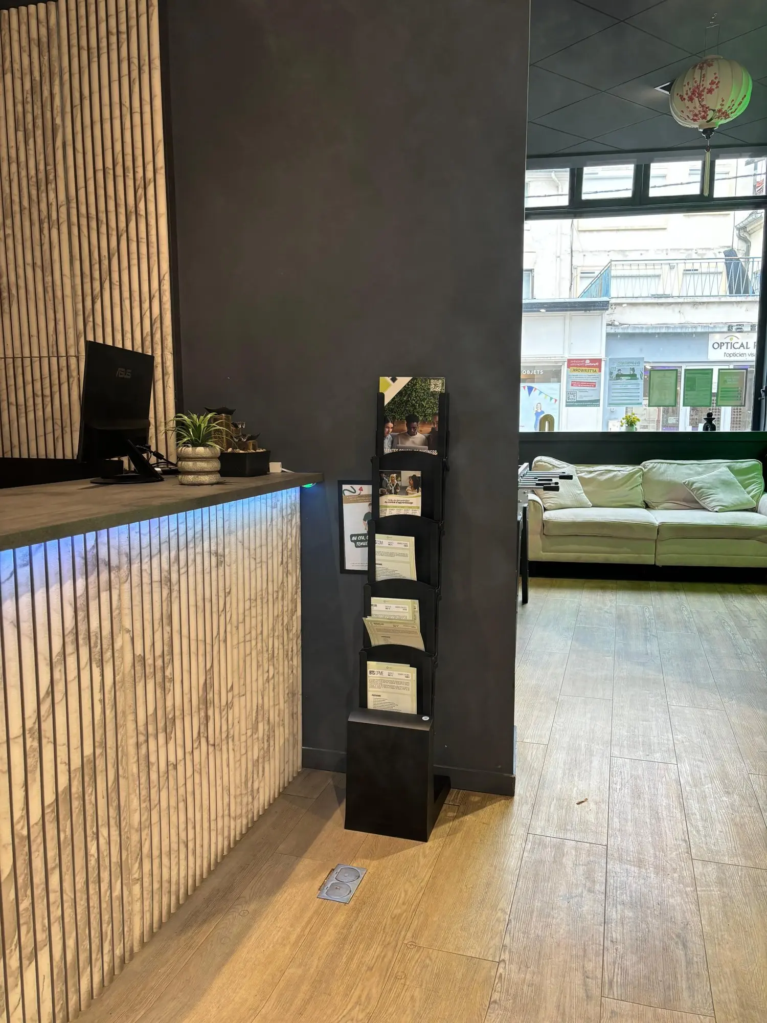 Banque d'accueil en bois clair, présentoir de brochures et espace d'attente