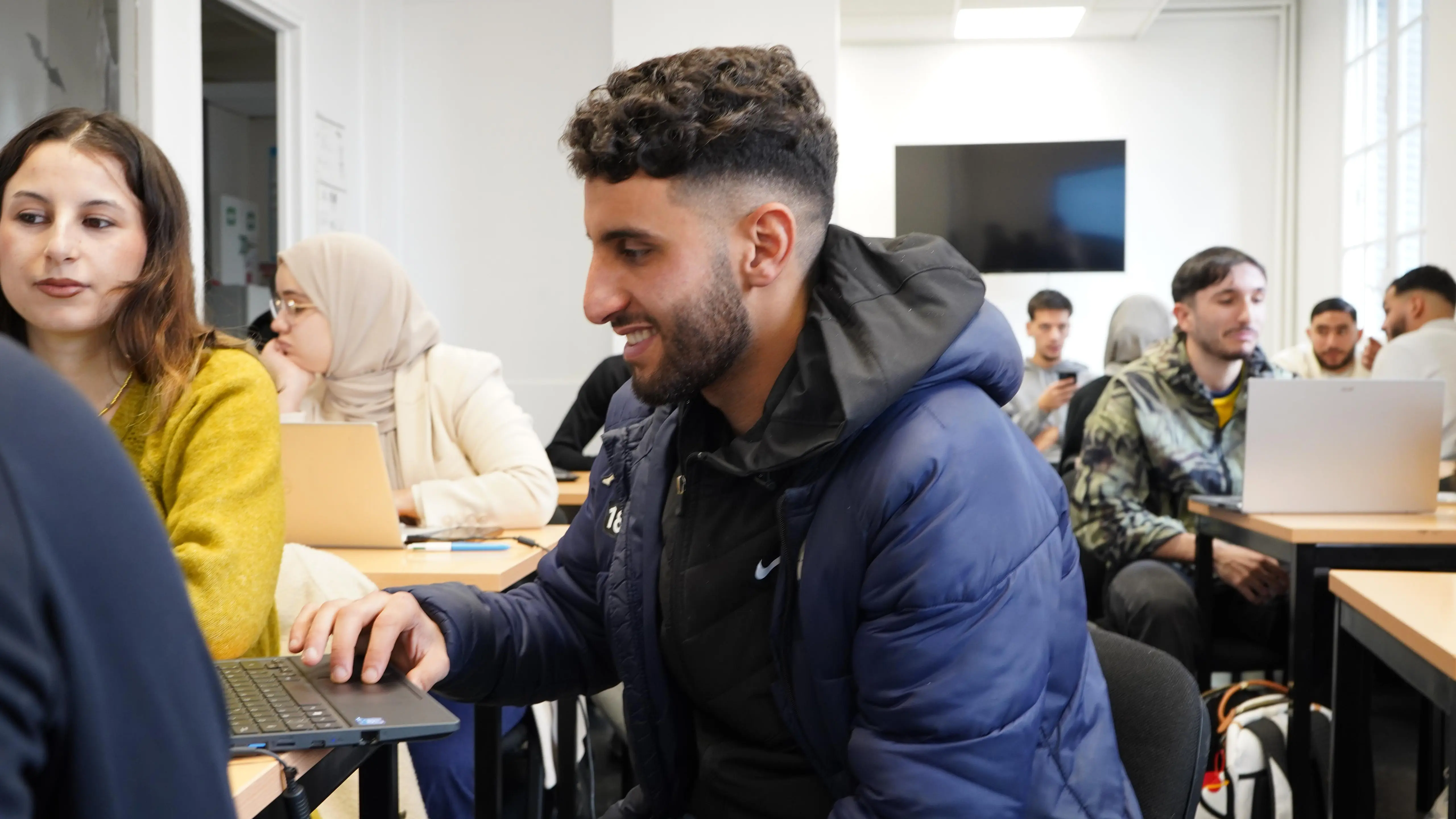 Étudiant souriant au travail sur ordinateur dans l'espace commun