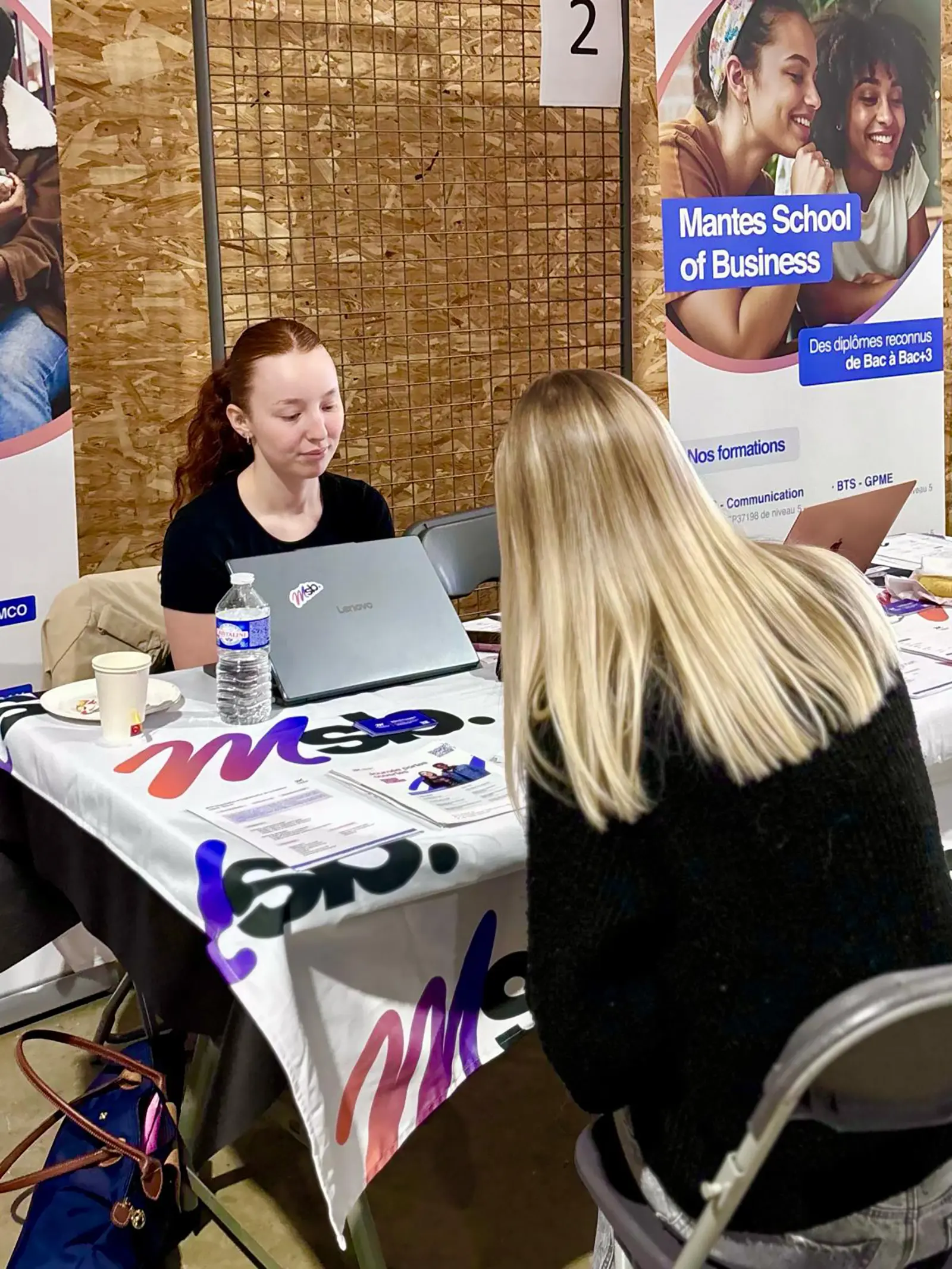 Étudiante en action commerciale sur le stand MSB, ordinateur ouvert